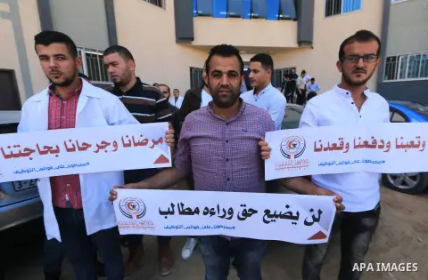 Palestinian Nurses hold banners during a protest to demand their rights, in Gaza city, on August 15, 2018. Photo by Mahmoud Khattab