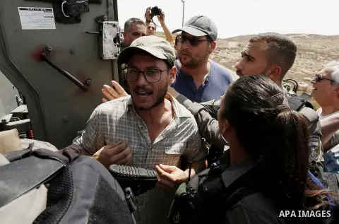 Israeli troops detain an Israeli activist during a protest against settlement, at Umm al-Arais in the village of Yatta, south of the West Bank city of Hebron, on August 31, 2018. Photo by Wisam Hashlamoun