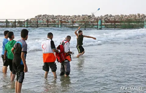 A Palestinian protester uses a slingshot to hurl stones towards Israeli troops during a demonstration against the Israeli blockade on Gaza Strip, along the Gaza sea barrier on the maritime border with Israel near Kibbutz...