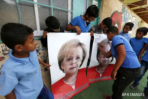 Palestinian students hold posters of German Chancellor Angela Merkel before her scheduled visit to Israel tomorrow, at the Palestinian Bedouin village of Khan al-Ahmar which Israel plan to demolish, in the occupied West...