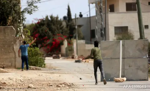 Palestinian protesters take cover from a tear gas canister fired by Israeli forces during clashes following a weekly demonstration against the expropriation of Palestinian land by Israel in the village of Kfar Qaddum, ne...