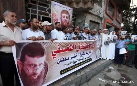 Palestinians hold posters of Islamic Jihad member Khader Adnan, who is in hunger strike at Israeli jails, during a protest calling for the release him, in Gaza city on October 16, 2018. Photo by Mahmoud Ajjour