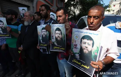 Palestinians hold posters of Islamic Jihad member Khader Adnan, who is in hunger strike at Israeli jails, during a protest calling for the release him, in Gaza city on October 16, 2018. Photo by Mahmoud Ajjour