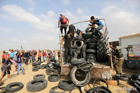 Palestinian protesters collect tires before burning it at Israel-Gaza border during a protest where Palestinians demand rights to return to their homeland, in Khan Younis in the southern Gaza Strip October 19, 2018. Phot...