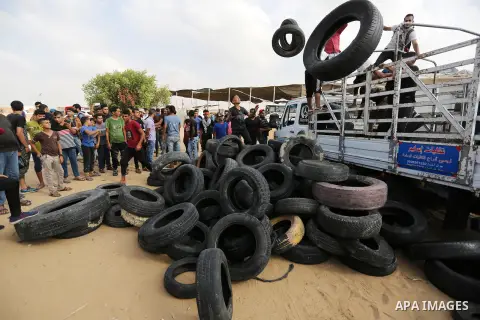 Palestinian protesters collect tires before burning it at Israel-Gaza border during a protest where Palestinians demand rights to return to their homeland, in Khan Younis in the southern Gaza Strip October 19, 2018. Phot...