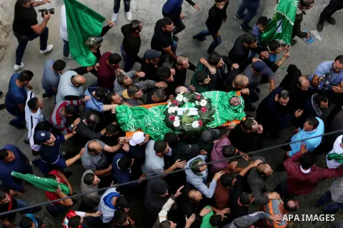 Mourners carry the body of Palestinian Othman Ladadwah, who was shot dead by Israeli forces during clashes the day before, during his funeral in the village of Al-Mazraa Al-Gharbeya, in the West Bank city of Ramallah on...