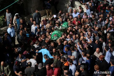 Mourners carry the body of Palestinian Othman Ladadwah, who was shot dead by Israeli forces during clashes the day before, during his funeral in the village of Al-Mazraa Al-Gharbeya, in the West Bank city of Ramallah on...