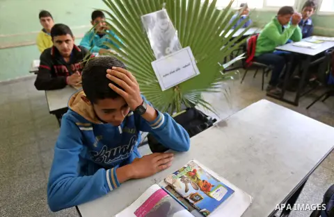 A picture of Palestinian boy Khaled Saed,14, who was killed in an Israeli air strike on the Gaza Strip, is seen on his study seat next to his classmates at a school, in Deir al-Balah in the central Gaza Strip, on October...