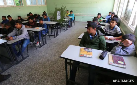 A picture of Palestinian boy Khaled Saed,14, who was killed in an Israeli air strike on the Gaza Strip, is seen on his study seat next to his classmates at a school, in Deir al-Balah in the central Gaza Strip, on October...