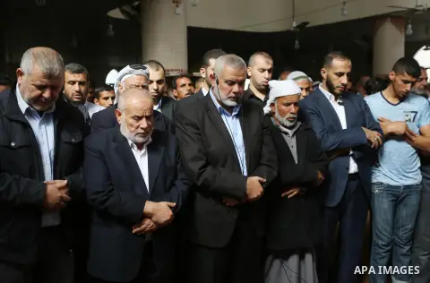 Palestinian Hamas Chief Ismail Haniyeh prays over the bodies of three Palestinian teenagers who were killed in an Israeli air strike on the Gaza Strip during their funeral in Deir el-Balah in central of the Gaza Strip on...