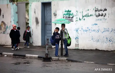 Palestinian students walk through a wet street during a rainy day in Gaza City on November 6, 2018. Photo by Mahmoud Ajjour