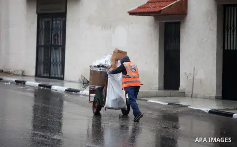A Palestinian Cleaner works in a street during a rainy day in Gaza City on November 6, 2018. Photo by Mahmoud Ajjour