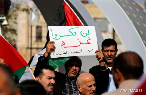 Palestinian protesters hold placards and national flags during a a rally to show solidarity with Palestinians in Gaza, in the West Bank city of Hebron on November 13, 2018. Photo by Wisam Hashlamoun