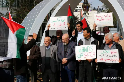 Palestinian protesters hold placards and national flags during a a rally to show solidarity with Palestinians in Gaza, in the West Bank city of Hebron on November 13, 2018. Photo by Wisam Hashlamoun