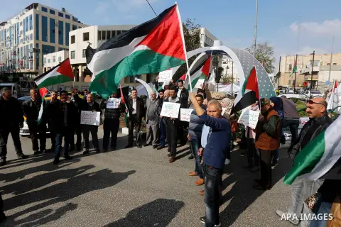 Palestinian protesters hold placards and national flags during a a rally to show solidarity with Palestinians in Gaza, in the West Bank city of Hebron on November 13, 2018. Photo by Wisam Hashlamoun