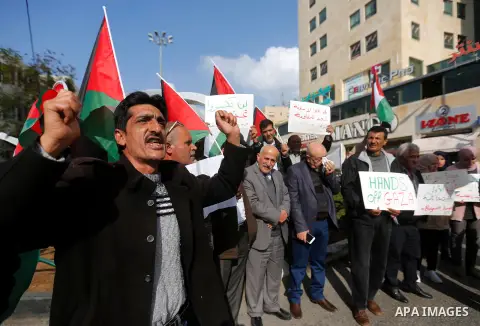 Palestinian protesters hold placards and national flags during a a rally to show solidarity with Palestinians in Gaza, in the West Bank city of Hebron on November 13, 2018. Photo by Wisam Hashlamoun