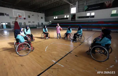A disabled Palestinian woman on a wheelchair Heda Abu Ouda, 38, takes part in a basketball lesson, at a club in Gaza City on November 27, 2018. Photo by Mahmoud Ajjour
