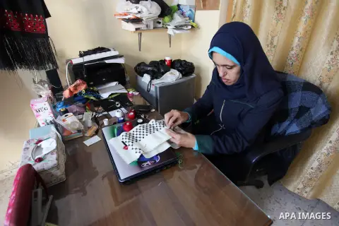 A disabled Palestinian woman Heda Abu Ouda, 38, works on a handmade embroidered products to sell its for customers at her workshop in Gaza City on November 27, 2018. Photo by Mahmoud Ajjour