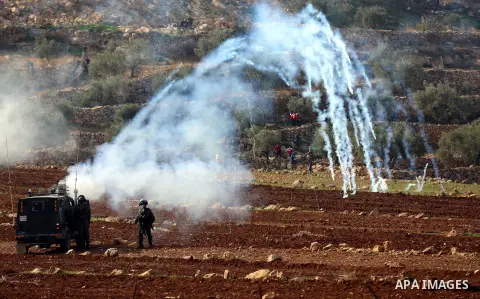 Tear gas canisters are fired by Israeli forces towards Palestinian protesters during a protest against Israeli land seizures for Jewish settlements, in the village of al-Mughayyir, near the West Bank city of Ramallah, on...