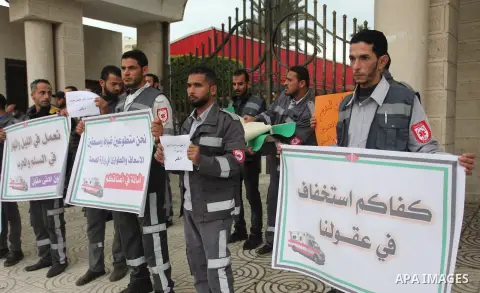 Palestinian Volunteers hold banners during a protest demanding their rights, in front of the Legislative Council, in Gaza city, on December 9, 2018. Photo by Mahmoud Ajjour