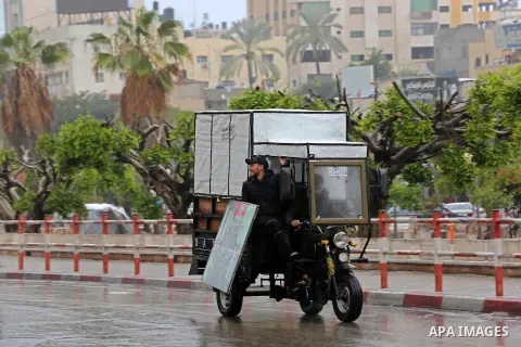 A Palestinian man rides a motorcycle during a rainy day in Gaza city on December 20, 2018. Photo by Ashraf Amra