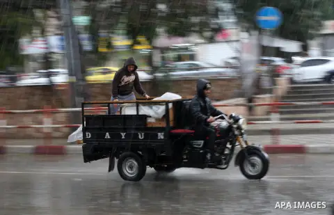 Palestinians ride a motorcycle during a rainy day in Gaza city on December 20, 2018. Photo by Ashraf Amra