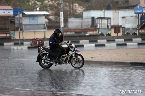 A Palestinian man rides a motorcycle during a rainy day in Gaza city on December 20, 2018. Photo by Ashraf Amra