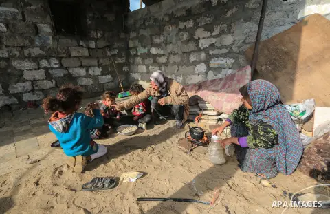A picture taken on December 20, 2018 shows a Palestinian family eat in front of their dwelling during winter season at Nahr al-Bared refugee camp in Khan Younis in the southern Gaza Strip. Photo by Mahmoud Khattab