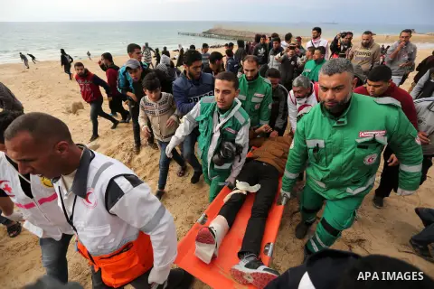 Paramedicals carry a wounded Palestinian protester, who was injured by Israeli security forces at the Gaza-Israel maritime border, during clashes across from the Israeli settlement of Kibbutz Zikim, on February 19, 2019,...