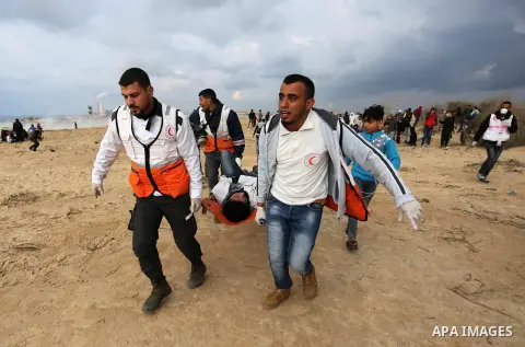 Paramedicals carry a wounded Palestinian protester, who was injured by Israeli security forces at the Gaza-Israel maritime border, during clashes across from the Israeli settlement of Kibbutz Zikim, on February 19, 2019,...