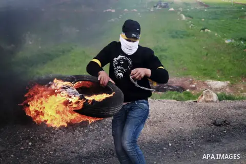 A Palestinian protester burns a tire during clashes with Israeli security forces following a protest against Israeli settlements, in al-Mughayyir village near the West Bank city of Ramallah, on February 22, 2019. Photo b...