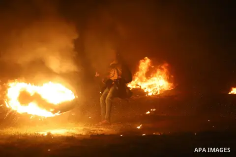 A member of Palestinian protesters calling themselves the "night confusion units", burns tires as they gather near the Gaza-Israel border east of Gaza city, March 23, 2019. Hundreds of Palestinian protesters, have been o...