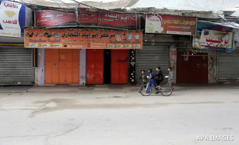 Palestinians walk past closed shops during a general strike marking the Land Day in Khan Younis in the southern Gaza strip on March 30, 2019. This year, Land Day coincides with the first anniversary of the Great March of...