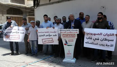 Palestinians hold placards during a protest against the economic workshop in Bahrain, in Gaza city on June 24, 2019. The Palestinian Ministry of Foreign Affairs said “Trump administration is re-producing the Palestinian-...