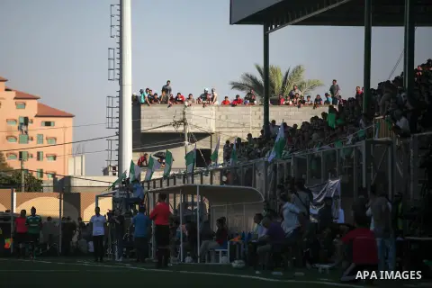 Fans shot slogans, as Palestinian players of Khadamat Rafah club (green T-shirt), and players of Balata youth club (yellow T-shirt), play during the Palestine cup championship, in Rafah in the southern Gaza Strip on June...