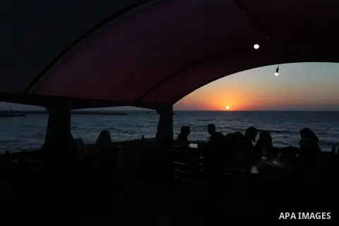 Palestinians site in a cafe on the beach ialong the shore of the Mediterranean Sea as they escape from the summer heat, in Gaza City July 01, 2019. Photo by Ashraf Amra