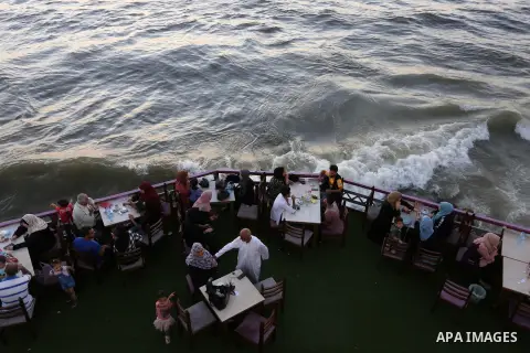 Palestinians site in a cafe on the beach ialong the shore of the Mediterranean Sea as they escape from the summer heat, in Gaza City July 01, 2019. Photo by Ashraf Amra