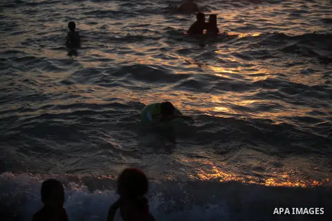 Palestinians enjoy at the beach along the shore of the Mediterranean Sea during the sunset, in Gaza City July 05, 2019. Photo by Mahmoud Ajjour