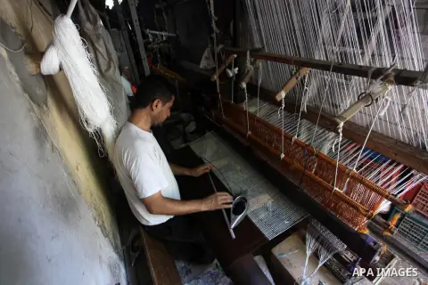 Palestinian workers weave carpets in a workshop in Gaza city on July 06, 2019. Weaving sheep's wool into traditional carpets is one oldest professions, it takes skill, patience and steady hand. Photo by Mahmoud Ajjour