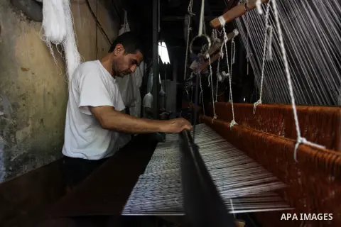 Palestinian workers weave carpets in a workshop in Gaza city on July 06, 2019. Weaving sheep's wool into traditional carpets is one oldest professions, it takes skill, patience and steady hand. Photo by Mahmoud Ajjour