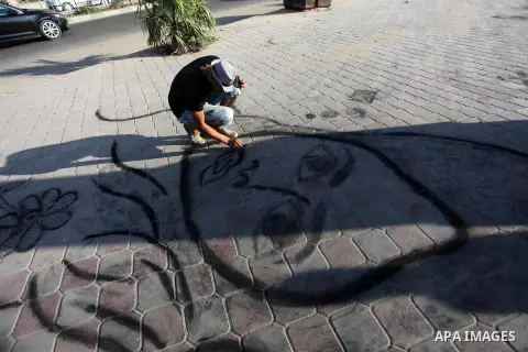 Moawia Ashour, 24, a Palestinian man uses coal to draw on the ground near his street cafe, at the beach of Gaza city, July 30, 2019. Photo by Mahmoud Ajjour