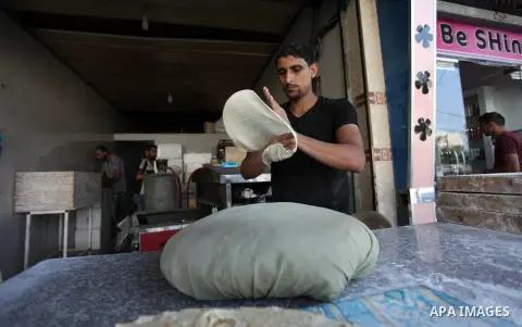 A Palestinian man bakes traditional bread "Taboon", in Gaza city, on September 22, 2019. Photo by Mahmoud Ajjour