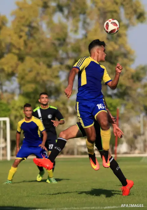 Palestinian football players of Etihad Beit Hanoun (blue) and Alhilal (Dark blue) compete during match premier League in Alyarmuk stadium, in Gaza City on September 22, 2019. Photo by Mahmoud Ajjour
