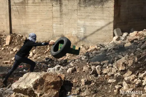 Palestinian protesters carry tires during clashes with Israel security forces following a weekly demonstration against the expropriation of Palestinian land by Israel in the village of Kfar Qaddum, near the West Bank cit...