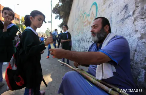 A Palestinian man sells sugar cane to students at a street, in Gaza city, on October 2, 2019. Photo by Mahmoud Ajjour