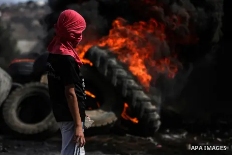 A Palestinian protester carry tires during clashes with Israel security forces following a weekly demonstration against the expropriation of Palestinian land by Israel in the village of Kfar Qaddum, near the West Bank ci...