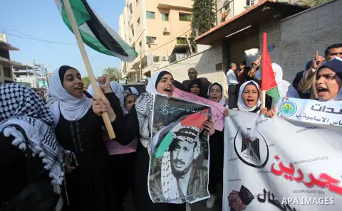 Palestinians hold pictures of the late Palestinian leader Yasser Arafat to mark the 15th anniversary of his death during a protest in solidarity with prisoners in Israeli jails, in front of the Red cross office, in Gaza...