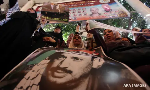 Palestinians hold pictures of the late Palestinian leader Yasser Arafat to mark the 15th anniversary of his death during a protest in solidarity with prisoners in Israeli jails, in front of the Red cross office, in Gaza...