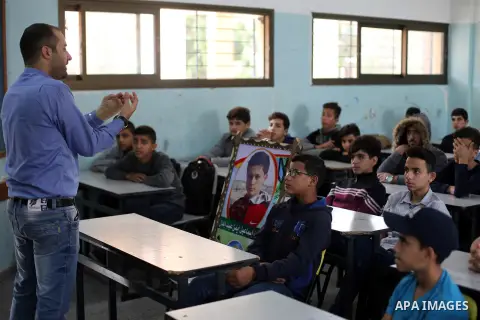 A picture of Palestinian student boy Ismail Abd El-Aal,16, who was killed in an Israeli air strike on the Gaza Strip, is seen on his study seat next to his classmates at a school, in Gaza City, on November 16, 2019. Phot...