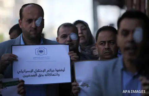 Palestinian journalists are pasted on the eyes during a protest to show solidarity with Muath Amarna, who was shot in his eye, in the Gaza city, on November 17, 2019. Photo by Mahmoud Ajjour